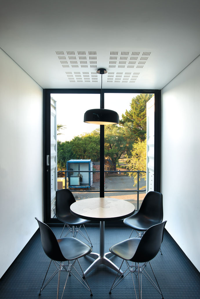 The table in this small meeting room was created by forming two wood offcuts into a jigsaw puzzle shape and placing it on a ready-made table base. The light fitting is from Spazio Lighting. 
